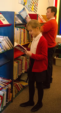 Photo of a girl and a boy standing at some shelves